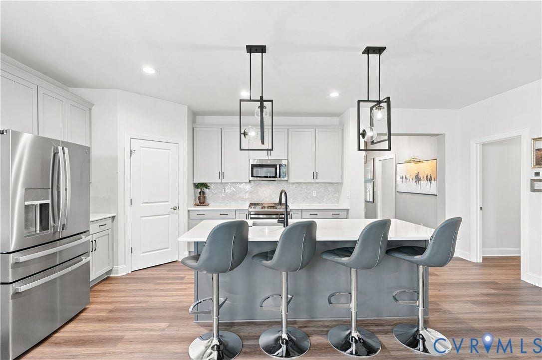 7437 Aldeby Street, Glen Allen, VA 23059 Kitchen featuring stainless steel appliances, wood-finish flooring, an island with countertop seating, white cabinetry, and decorative pendant lighting