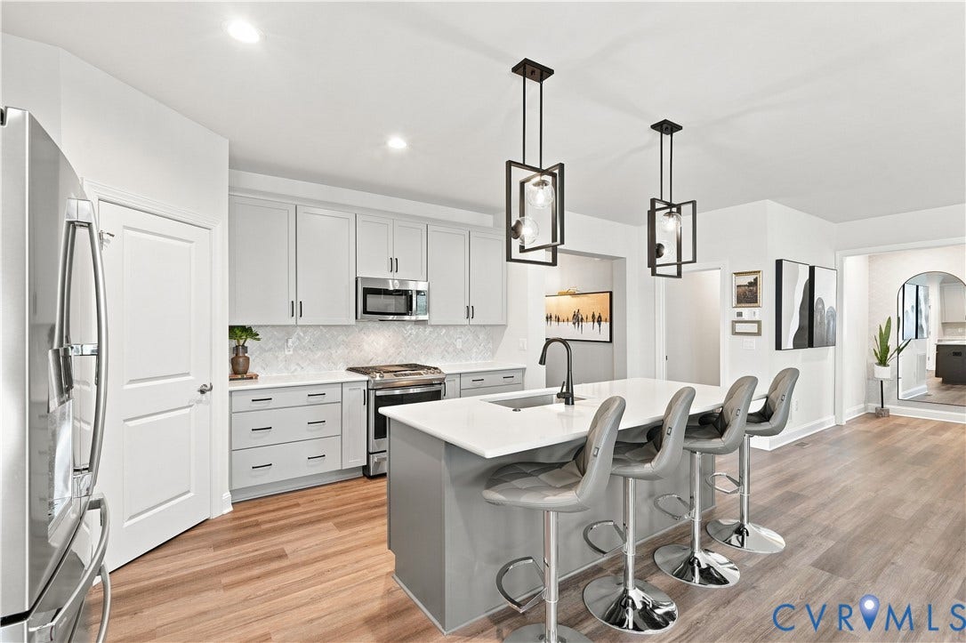 7437 Aldeby Street, Glen Allen, VA 23059 Gourmet kitchen with wood-finish flooring, white shaker cabinetry, stainless steel appliances, and a central island with a solid surface countertop