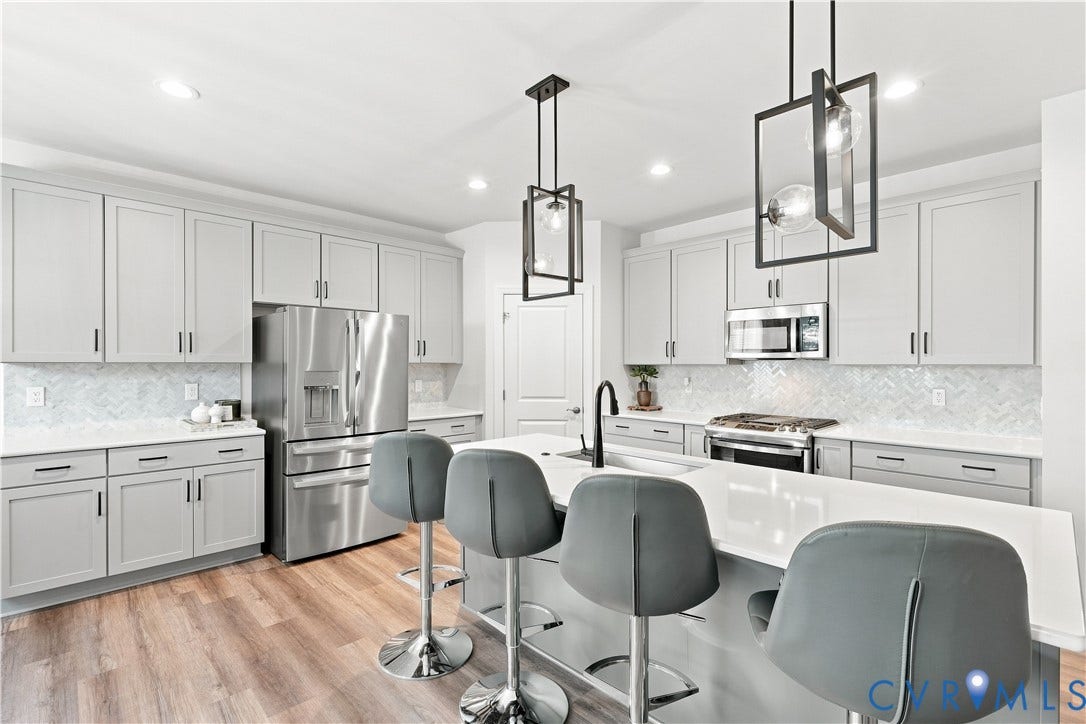 7437 Aldeby Street, Glen Allen, VA 23059 Modern kitchen with light gray cabinetry, stainless steel appliances, a white countertop island, and wood-finish flooring
