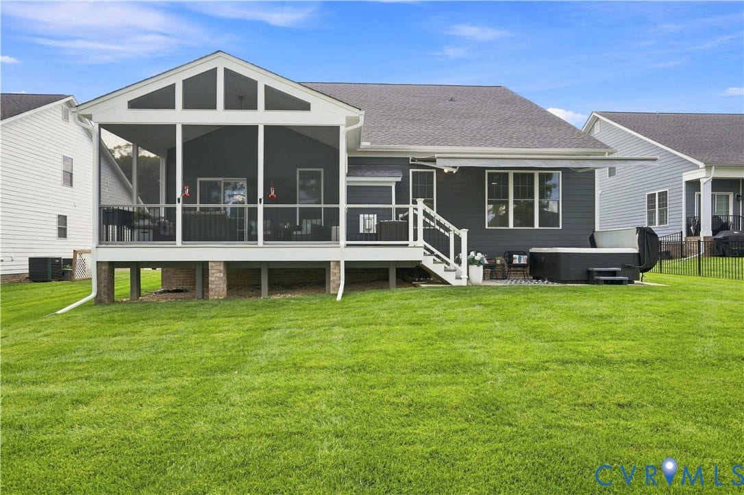 7437 Aldeby Street, Glen Allen, VA 23059 Expansive green lawn with a screened porch, dark gray siding, and a white-railed staircase descending to a paved patio area