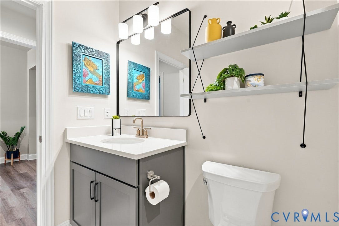 7437 Aldeby Street, Glen Allen, VA 23059 White countertop vanity with gray cabinet doors, a bronze-finish faucet, and an overhead rectangular mirror with an integrated light fixture