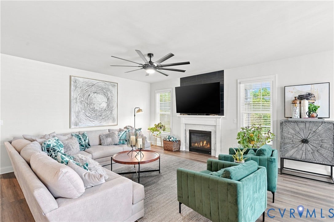 7437 Aldeby Street, Glen Allen, VA 23059 Spacious living area featuring wood-finish flooring, a contemporary ceiling fan, and a gas fireplace with a white mantel and dark tile surround