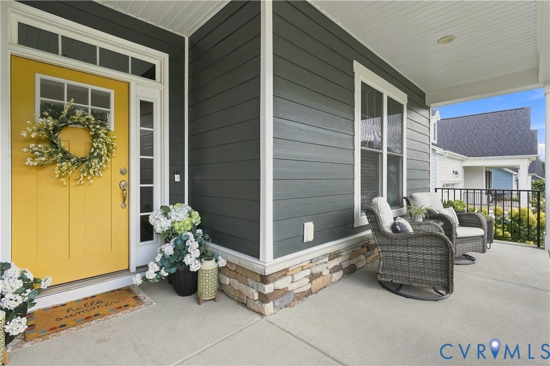 7437 Aldeby Street, Glen Allen, VA 23059 Covered front porch featuring stacked stone accents, dark gray horizontal siding, and a bright yellow paneled entry door with transom and sidelight windows