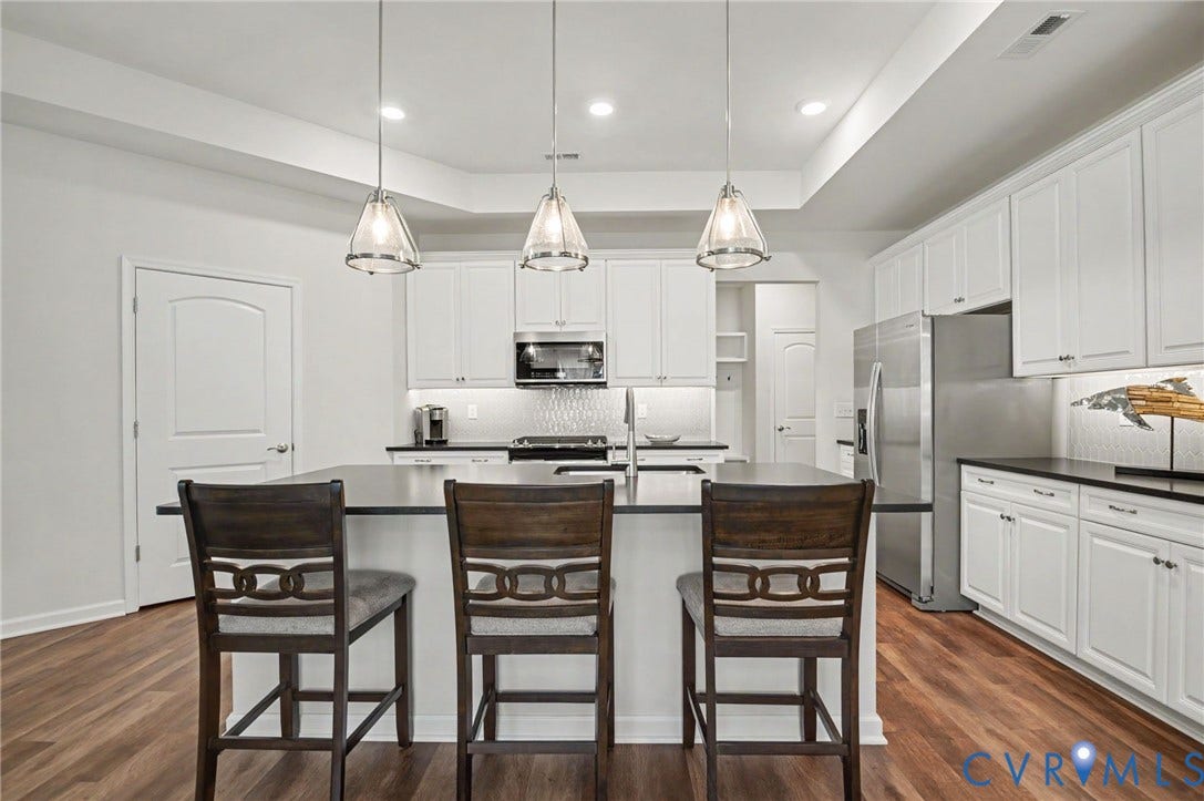 11618 Orchard Falls Circle, Chickahominy Falls, Glen Allen, VA 23059 Modern kitchen featuring an island with seating, pendant lighting, stainless steel appliances, white cabinetry, and wood-finish flooring