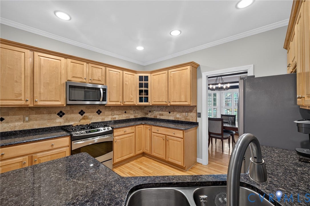 12320 Bradford Landing Way, Glen Allen, VA 23059 Kitchen featuring wood-finish cabinetry, dark speckled countertops, and a tile backsplash with decorative diamond accents