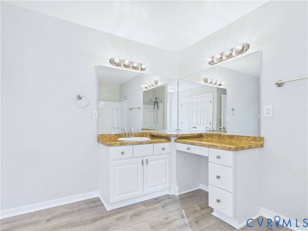 4515 Exton Lane, Chester, VA 23831 Dual vanity with integrated sink, built-in makeup counter, wood-finish flooring, and wall-mounted lighting