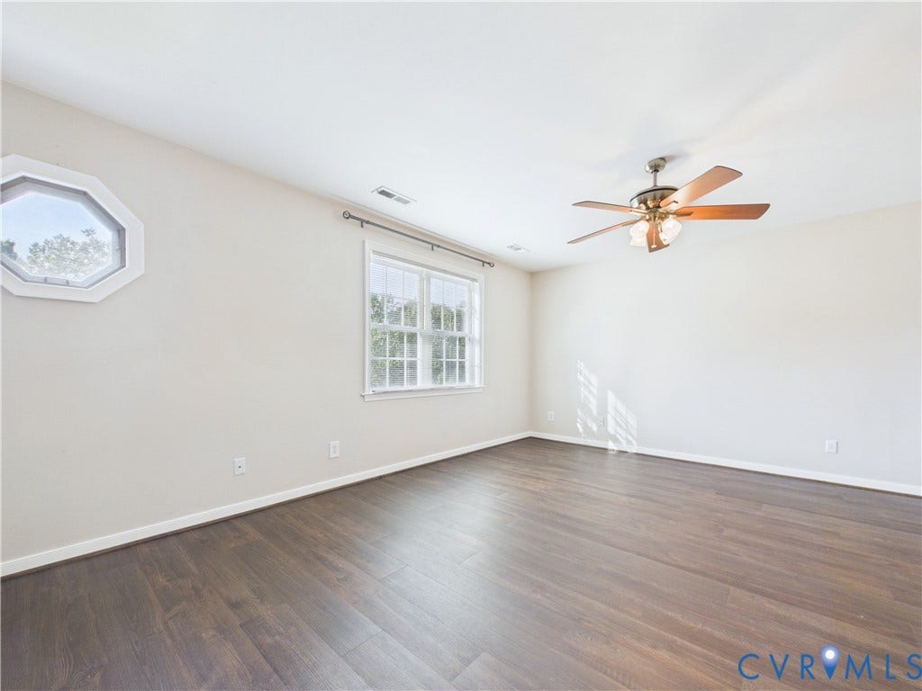4515 Exton Lane, Chester, VA 23831 Expansive room featuring wood-finish flooring, a multi-pane window, an octagonal accent window, and a ceiling fan with integrated lighting