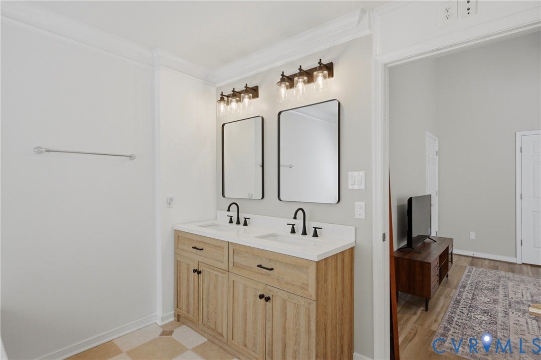 Dual vanity featuring light wood-finish cabinetry, white countertops, and matte black fixtures