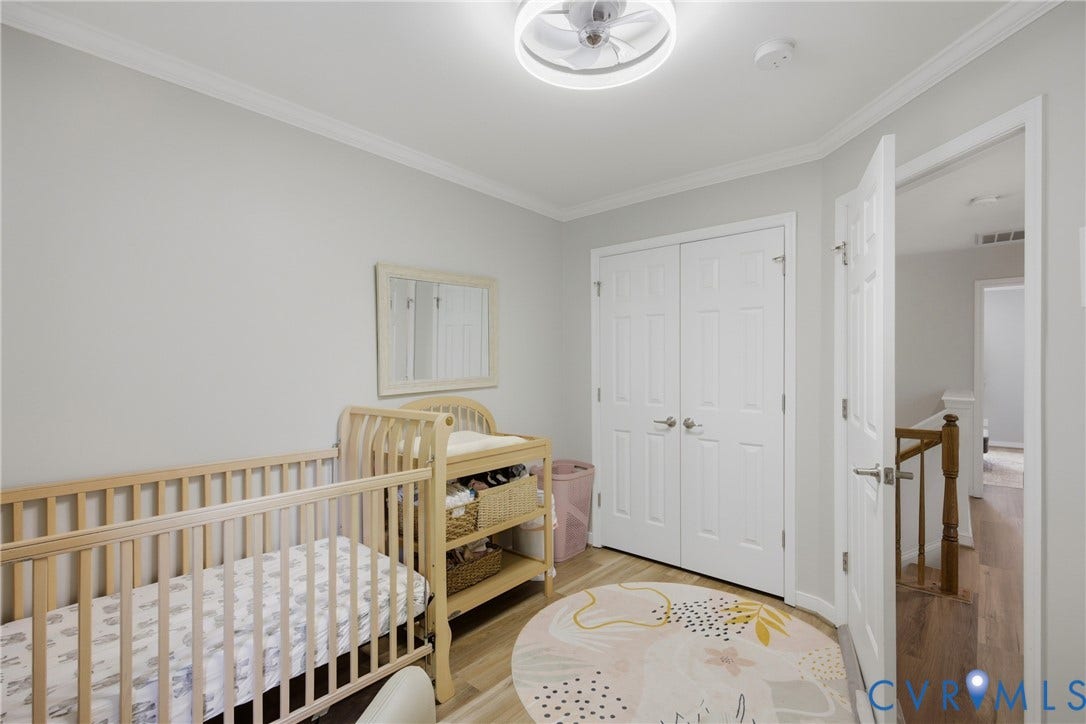 Room with light gray walls, crown molding, and wood-finish flooring