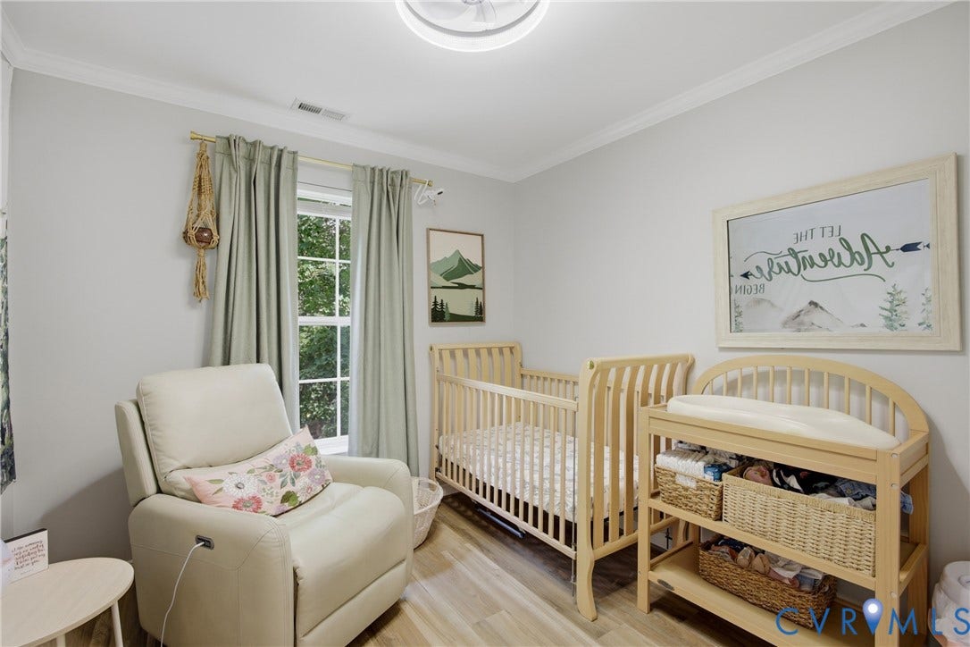 Bright interior space featuring light-colored flooring, crown molding, and a window with natural light