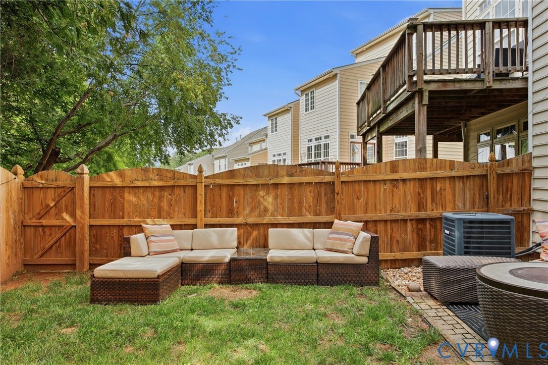 Fenced backyard with natural wood fencing, a grass lawn, and a paved brick section