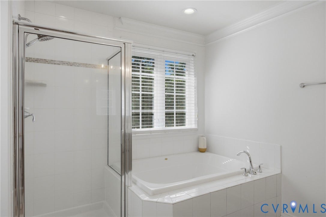 Bathroom featuring a built-in soaking tub with polished chrome fixtures, a tiled shower with glass enclosure, and a window with blinds