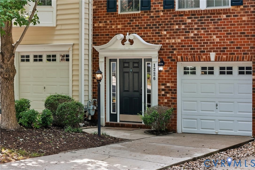 Brick facade with decorative white entryway surround, featuring a dark panel door with sidelights