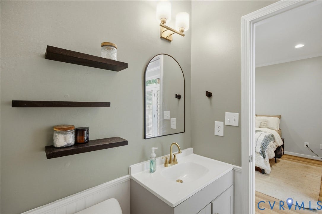 Elegant primary bathroom featuring a floating vanity with white rectangular sink, brass faucet, and quartz countertop