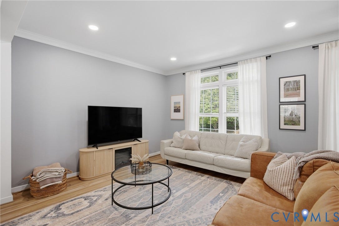 Recessed ceiling lighting illuminates a room with light-toned walls and wood-finish flooring