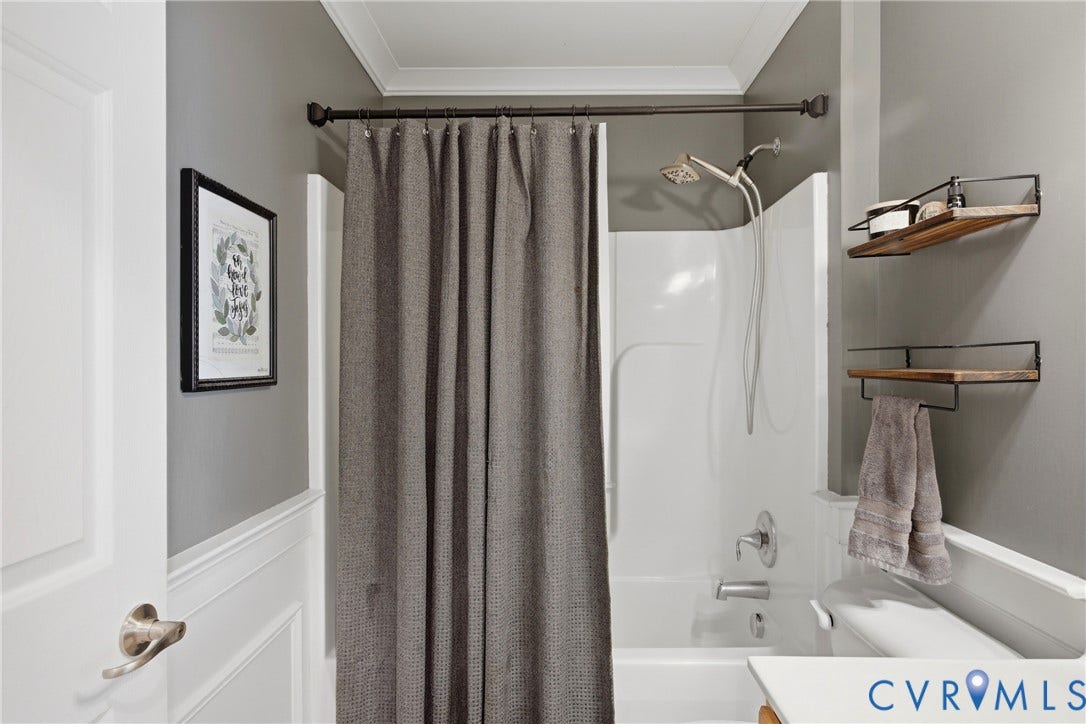 Modern bathroom featuring a clean white subway tile surround, brushed bronze hardware, and neutral gray walls