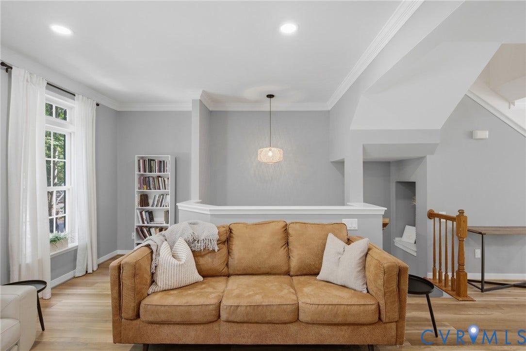 Bright, open living area showcasing a caramel leather sofa, hardwood flooring, and recessed ceiling lighting
