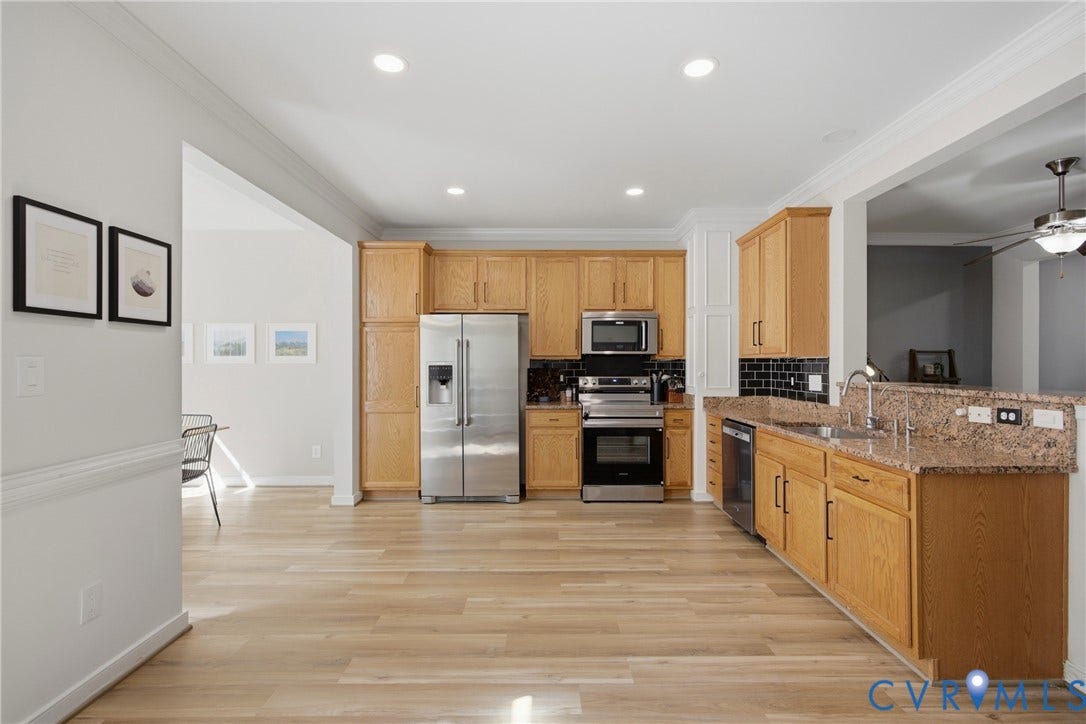 Open-concept kitchen featuring light wood-finish flooring, recessed lighting, and stainless steel appliances
