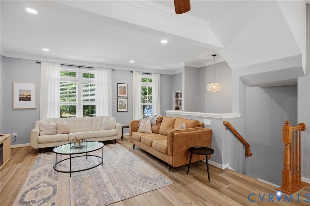 Spacious living area featuring wood-finish flooring, recessed lighting, and multiple windows with white blinds