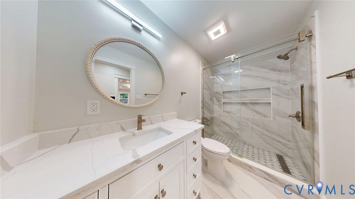 Modern bathroom featuring a single vanity with stone-finish countertop, undermount sink, and brushed brass faucet