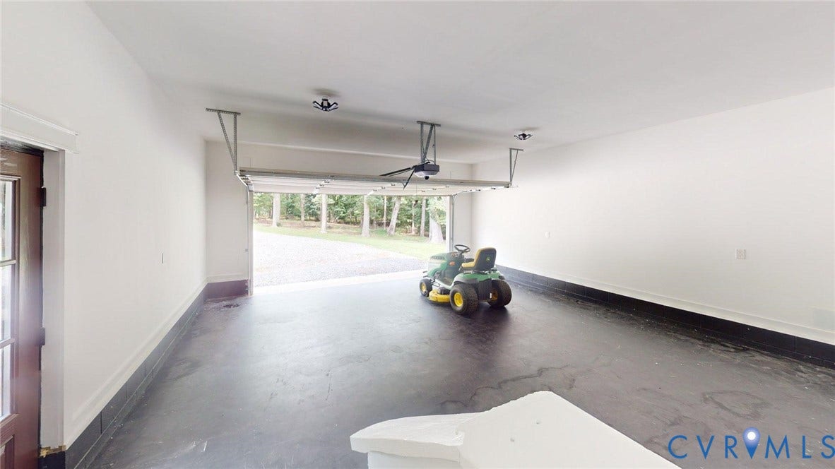Spacious garage featuring polished concrete flooring, overhead garage door with automatic opener, and abundant natural light from large front-facing windows