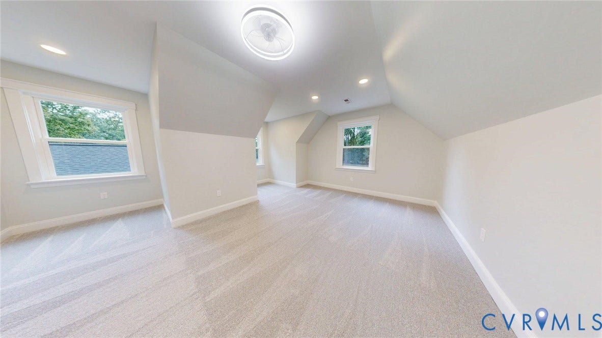 Expansive room featuring light gray carpet, multiple windows, a ceiling fan, and recessed lighting