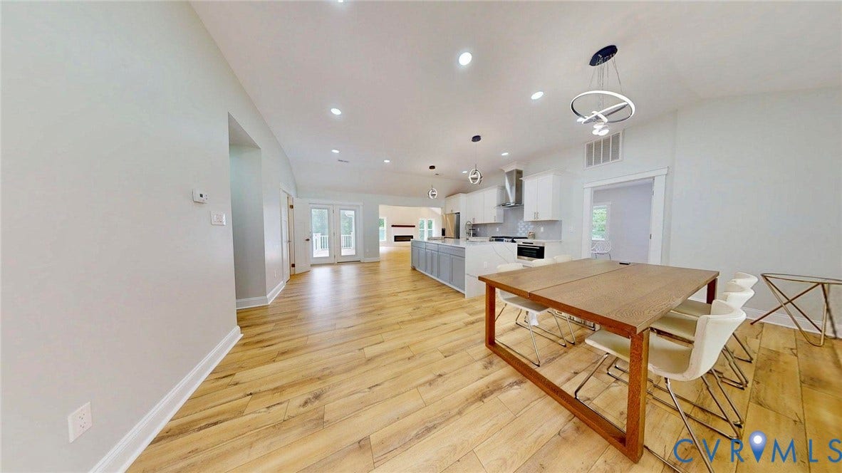 Open-concept interior featuring wood-finish flooring, recessed lighting, and a kitchen with an island, stainless steel appliances, and a range hood