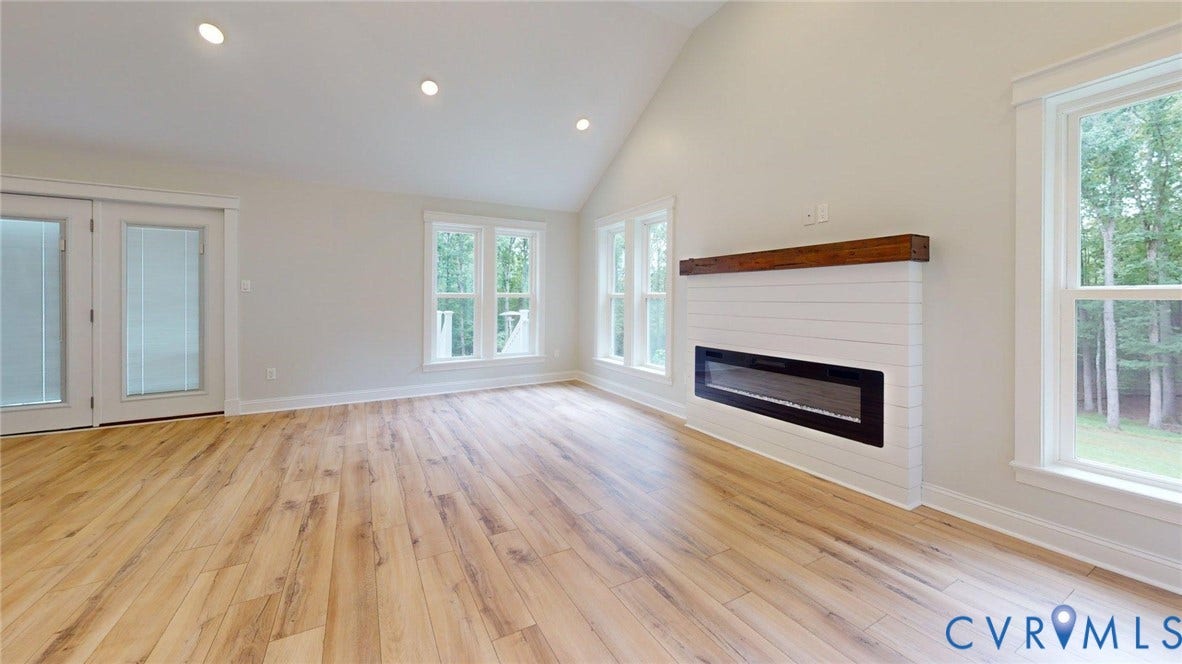 Spacious room featuring wood-finish flooring, a vaulted ceiling, and recessed lighting