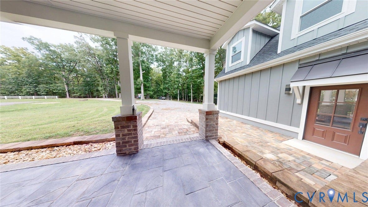 Covered entry with stamped concrete flooring and brick-clad columns