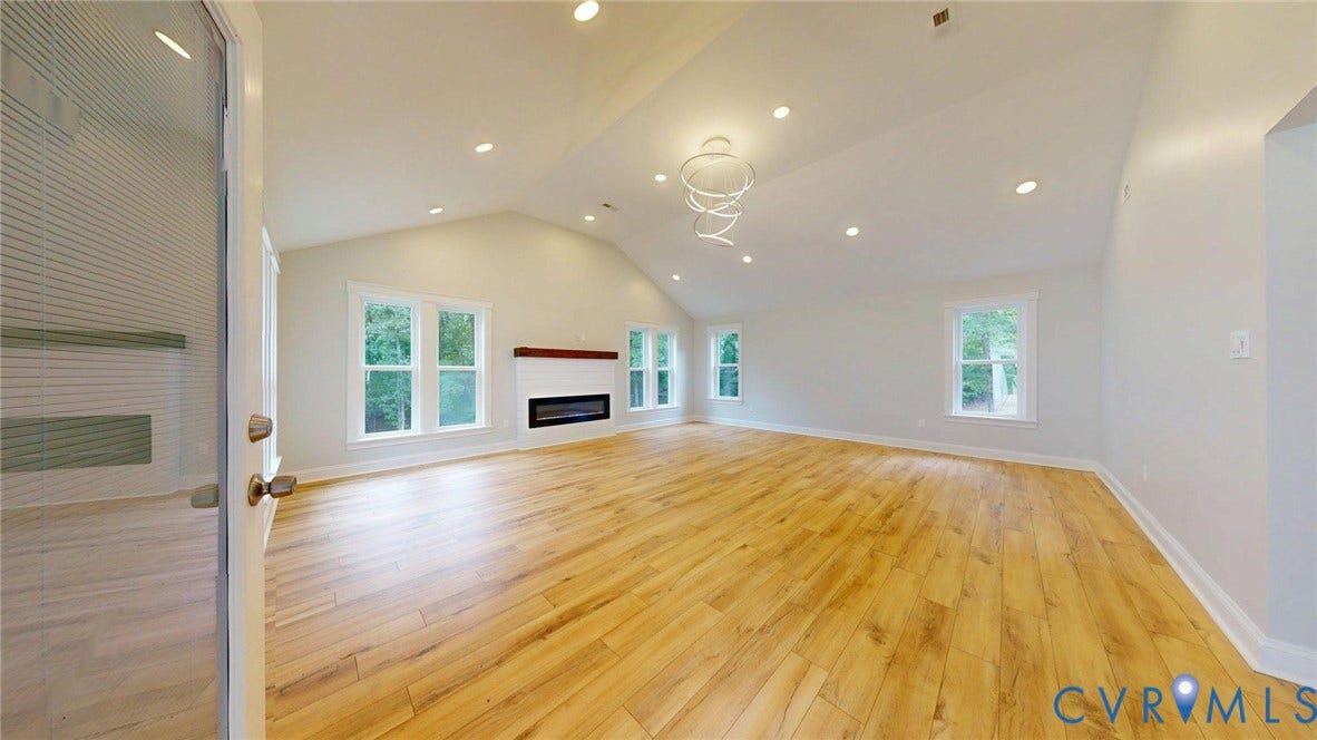 Vaulted ceiling great room featuring wood-finish flooring, recessed lighting, and a modern linear fireplace with a wood mantle