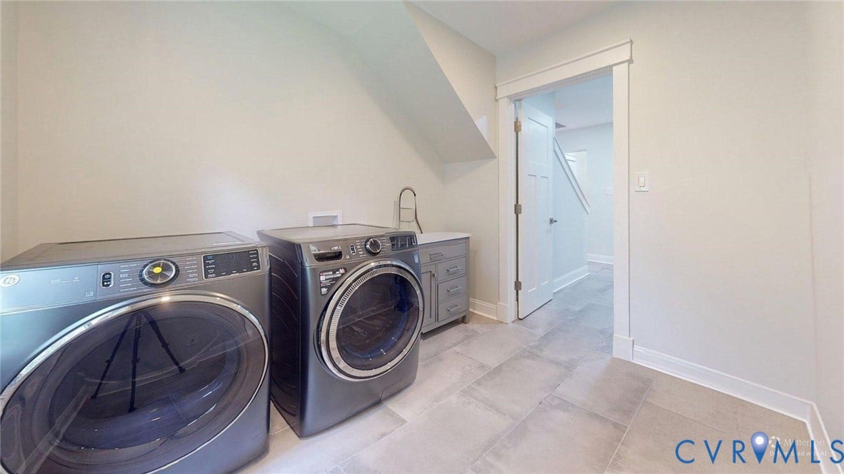 Dedicated laundry space featuring a utility sink, cabinet storage, and light-toned tile flooring