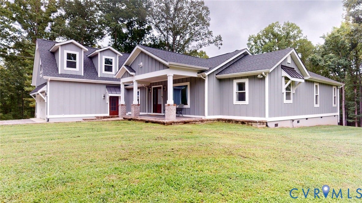 Craftsman-style home featuring light gray siding with white trim, a dark asphalt shingle roof, and a covered front porch with stone-wrapped columns
