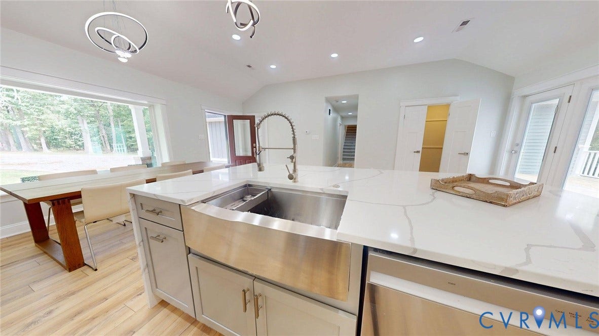 Kitchen island with a farmhouse sink, stainless steel appliances, and a light-toned countertop