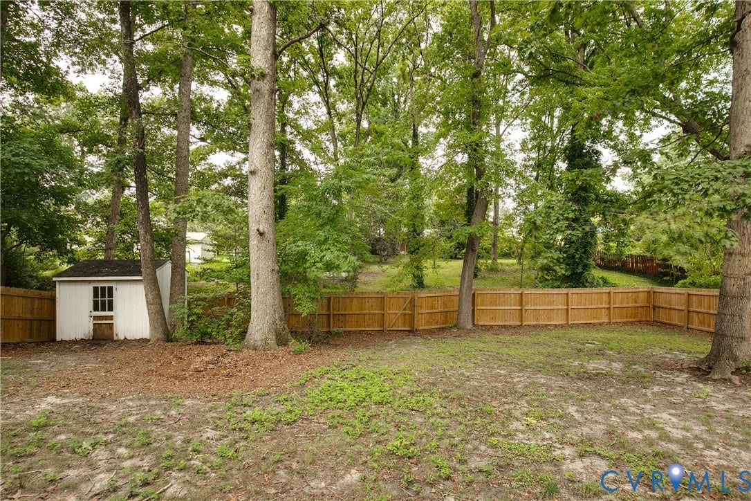 200 Stanmore Road, North Chesterfield, VA 23236 Private backyard featuring a wooden privacy fence, mature trees, and an auxiliary storage shed