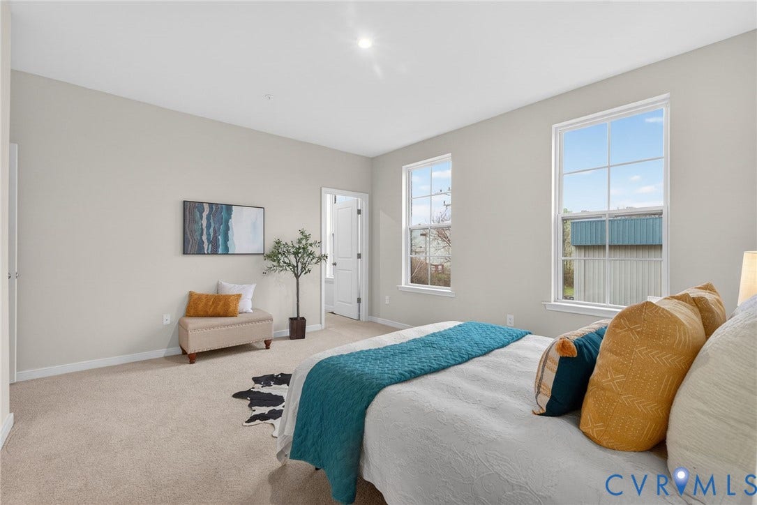 2439 Ownby Lane, #B 13, Richmond, VA 23220 Bright primary bedroom showcasing abundant natural light through dual large windows, neutral carpeting, recessed ceiling lighting, and a generous floor plan with direct access to an ensuite bathroom and walk-in closet