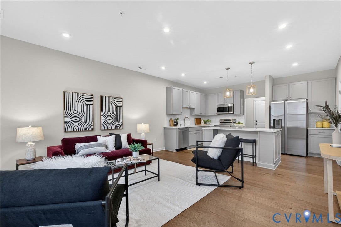 2439 Ownby Lane, #B 13, Richmond, VA 23220 Open-concept living and kitchen space featuring recessed ceiling lighting, wood-finish flooring throughout, stainless steel appliances, white cabinetry with integrated storage, and a dedicated work station with black metal framing