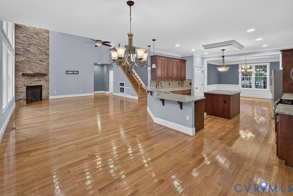 8825 First Branch Lane, Chesterfield, VA 23838 Hardwood flooring throughout, a stone-accented fireplace with wood mantel, a kitchen island with granite countertops, and a built-in kitchen island