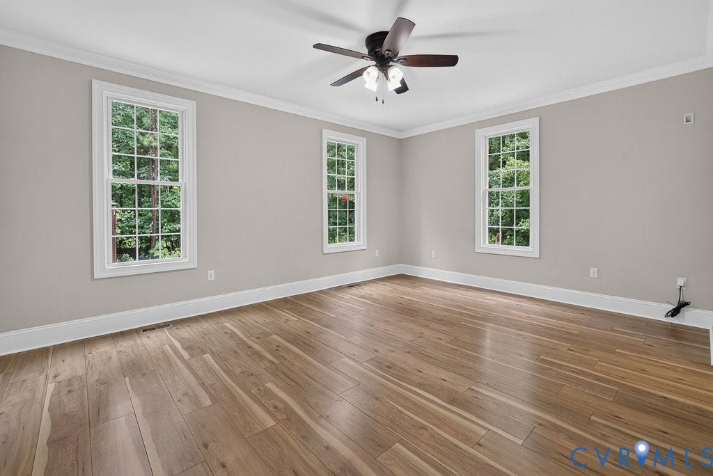 8825 First Branch Lane, Chesterfield, VA 23838 Wood-finish flooring, three double-hung windows, crown molding, and a ceiling fan with integrated lighting