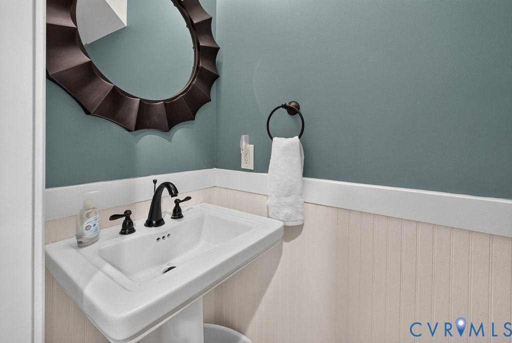 8825 First Branch Lane, Chesterfield, VA 23838 Pedestal sink with dark bronze faucet, beadboard wainscoting, and a decorative mirror