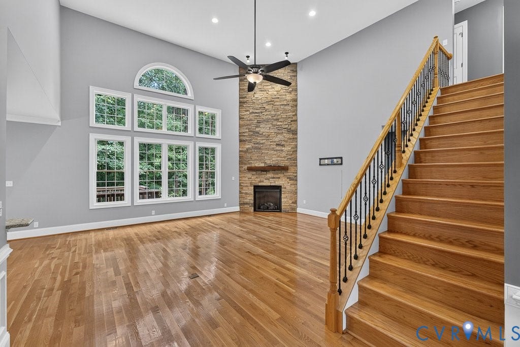 8825 First Branch Lane, Chesterfield, VA 23838 Vaulted ceiling with recessed lighting, wood-finish flooring, stone-clad fireplace, and a full-light window wall with an arched transom