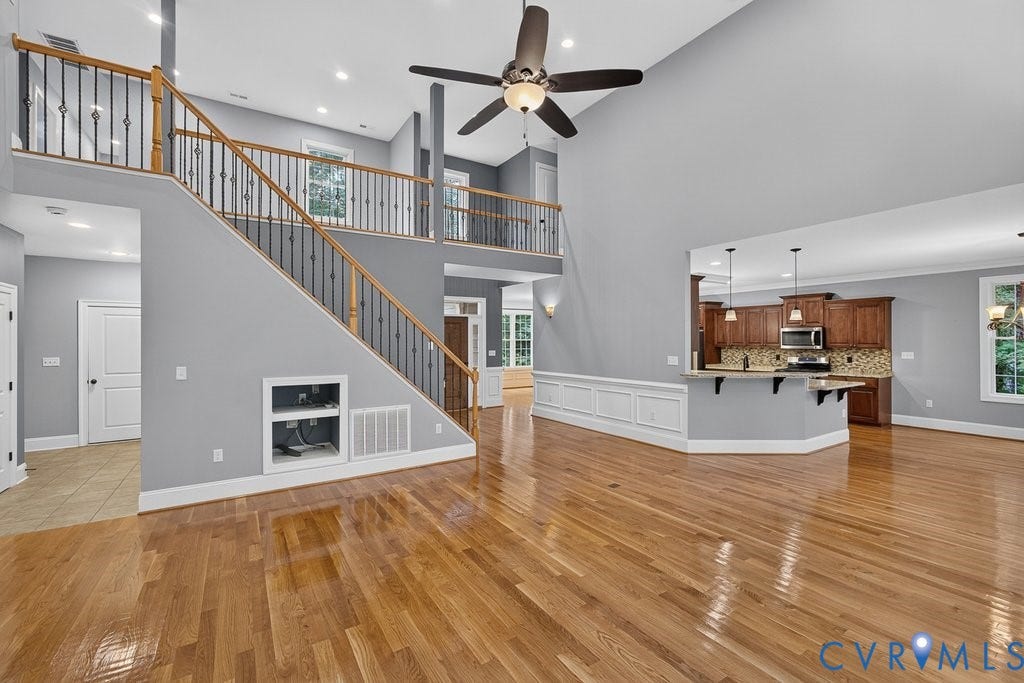 8825 First Branch Lane, Chesterfield, VA 23838 Vaulted ceiling with a ceiling fan, wood-finish flooring, staircase with wood handrails and wrought iron balusters, interior balcony, and a kitchen island with pendant lighting