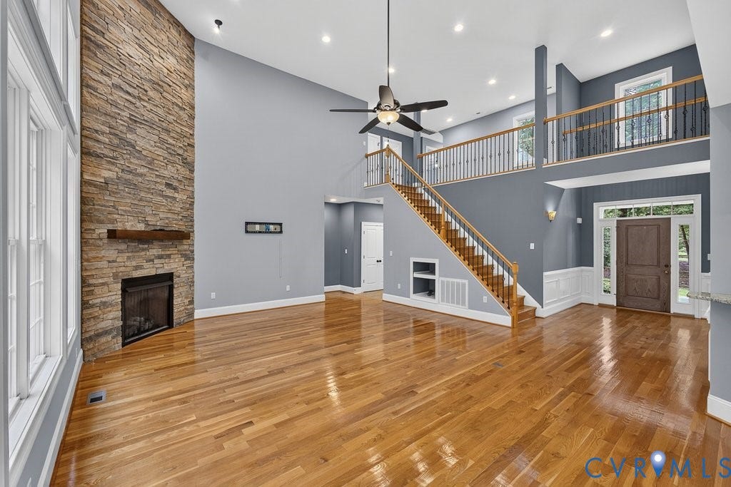 8825 First Branch Lane, Chesterfield, VA 23838 Hardwood flooring throughout, two-story stone fireplace with wood mantel, vaulted ceilings, open-tread staircase with wood handrails, and a second-story balcony