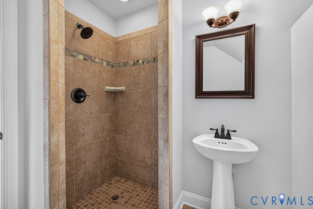 8825 First Branch Lane, Chesterfield, VA 23838 Shower with tiled walls and mosaic accent, dark bronze fixtures, and a coordinating pedestal sink with dark bronze faucet