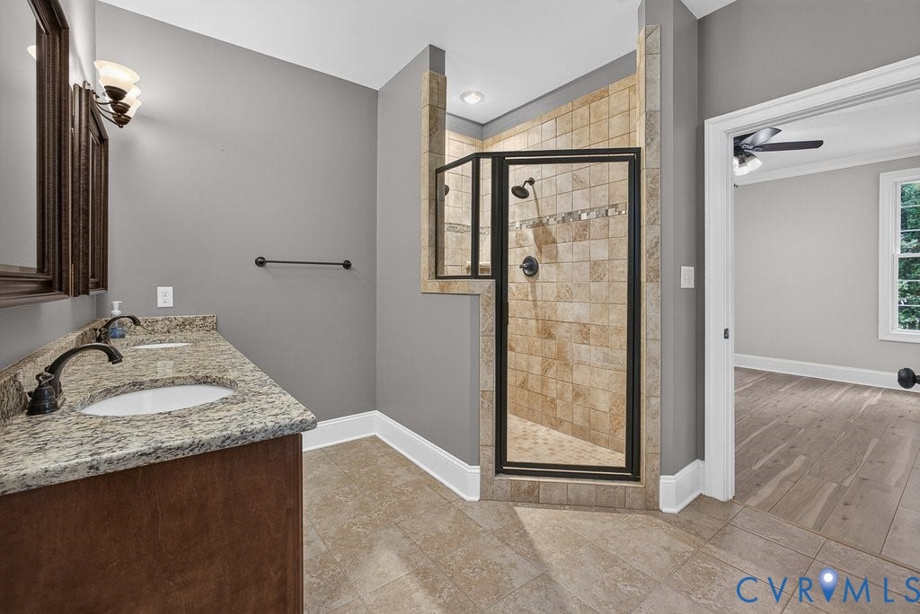 8825 First Branch Lane, Chesterfield, VA 23838 Dual vanity with stone countertop, tile flooring, and a tiled shower with glass enclosure