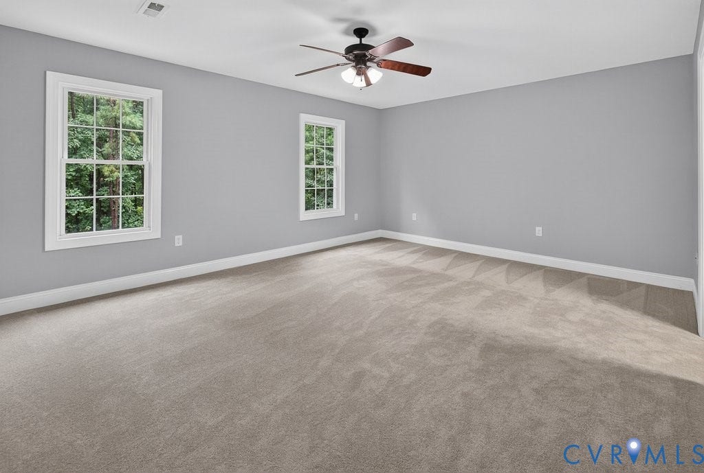 8825 First Branch Lane, Chesterfield, VA 23838 Spacious room featuring neutral carpeting, two double-hung windows with white trim, and a ceiling fan with integrated lighting