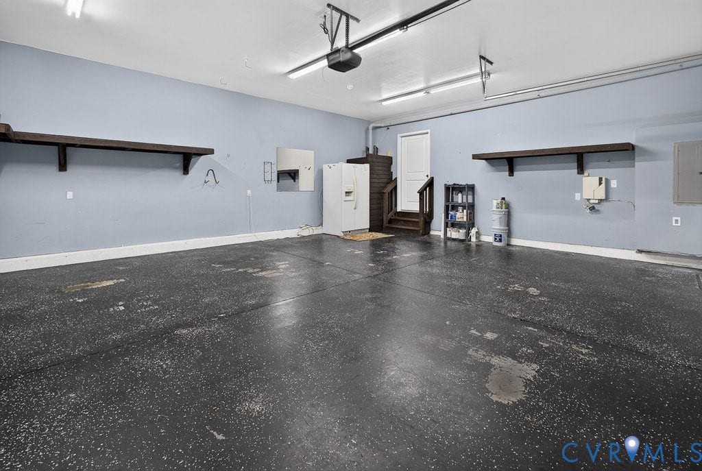 8825 First Branch Lane, Chesterfield, VA 23838 Spacious garage with light blue walls, built-in wooden shelving, and a painted concrete floor