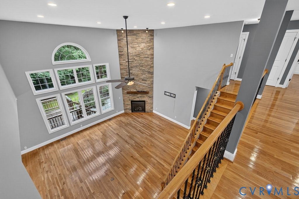 8825 First Branch Lane, Chesterfield, VA 23838 Vaulted ceiling with an arched window, stacked stone fireplace, wood-finish flooring, and a ceiling fan