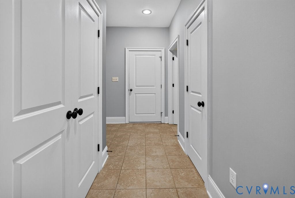 8825 First Branch Lane, Chesterfield, VA 23838 Bright hallway with crisp white six-panel doors, black hardware, and warm tile flooring throughout