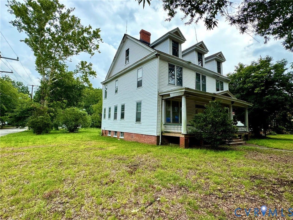 3521 Montrose Avenue, Ginter Park, Richmond, VA 23222 Multi-level residential structure featuring white siding, a covered porch, multiple dormer windows, a prominent brick chimney, and a surrounding lawn area with mature trees