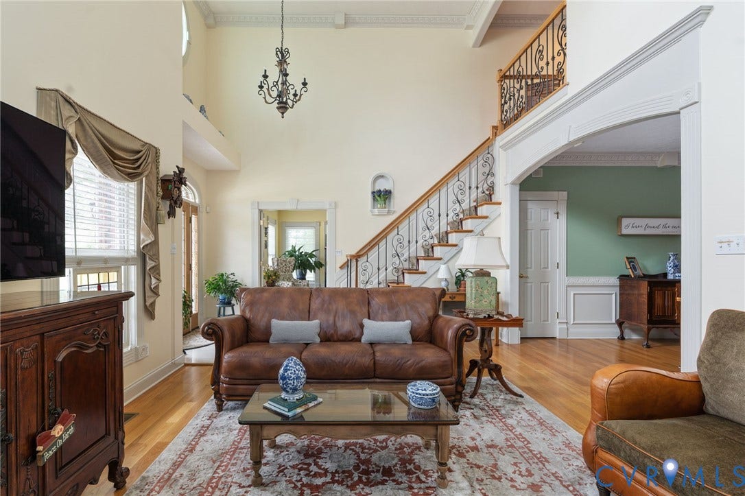 Grand two-story living area featuring a prominent staircase with wrought iron balusters and wood treads